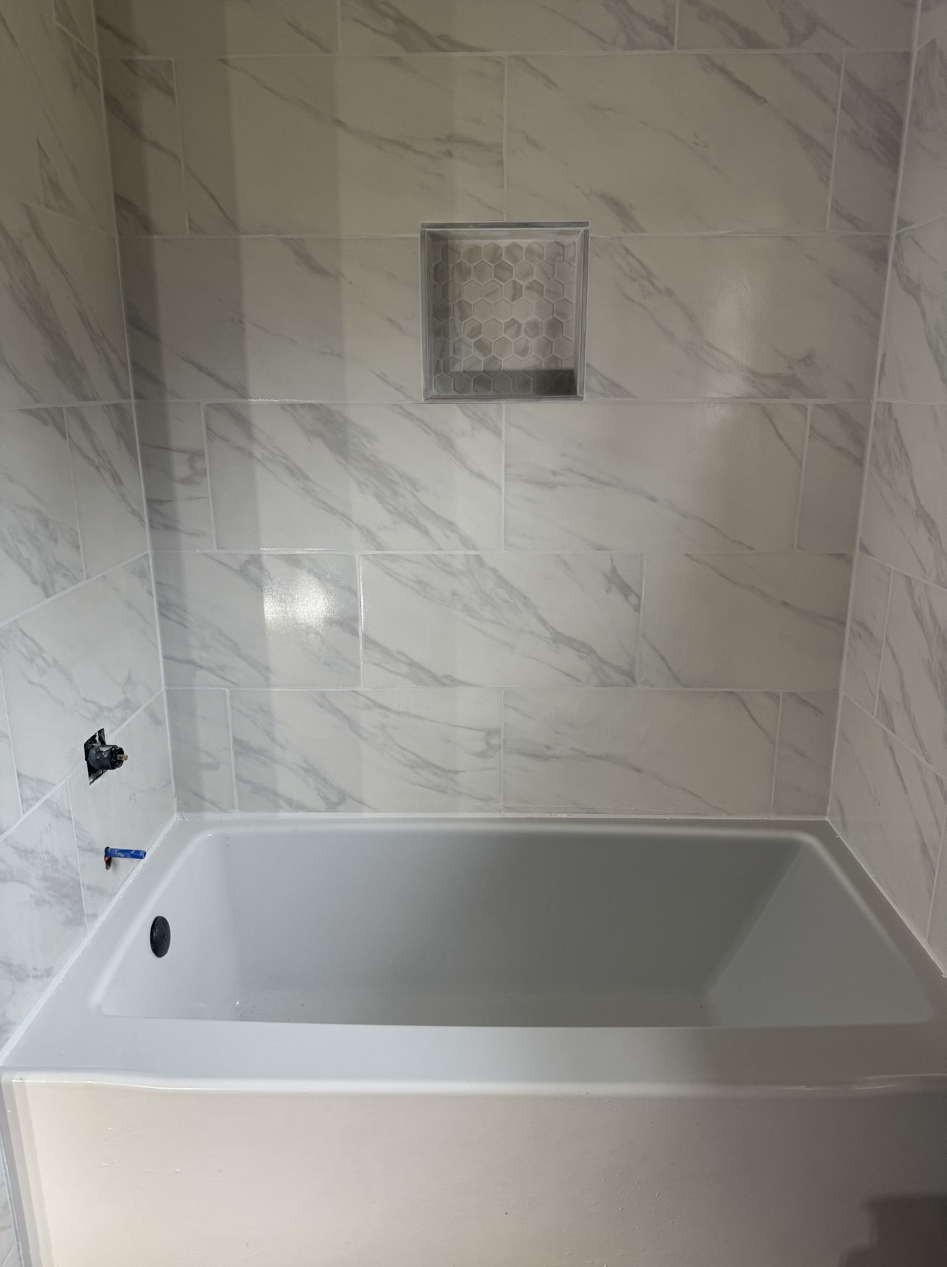 A bathroom with a toilet , tub , and washer and dryer.