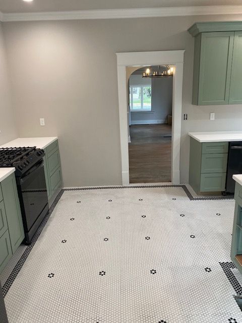 A kitchen with green cabinets and a white tile floor