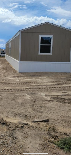 A mobile home is sitting in the middle of a dirt field.