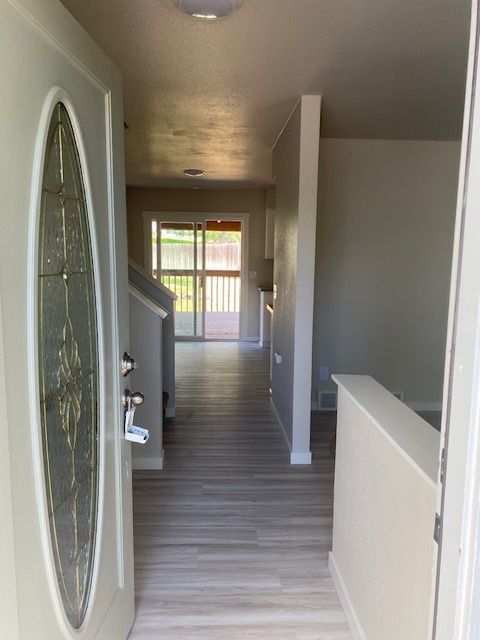 A white door with a stained glass window is open to a hallway leading to a living room.