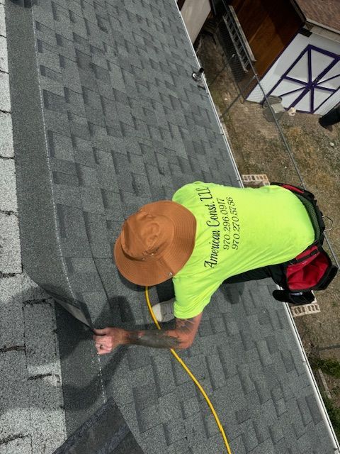 A man is working on a roof with a shirt that says ' jackson county llc ' on the back