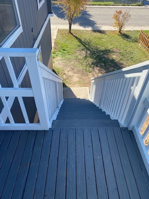 A deck with stairs leading up to it and a white railing.