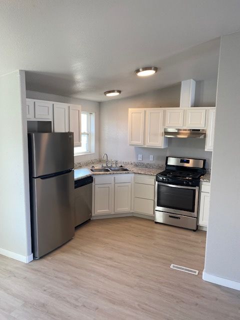 A kitchen with stainless steel appliances and white cabinets.