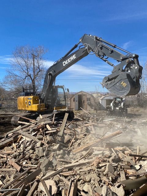 A deere excavator is demolishing a building.