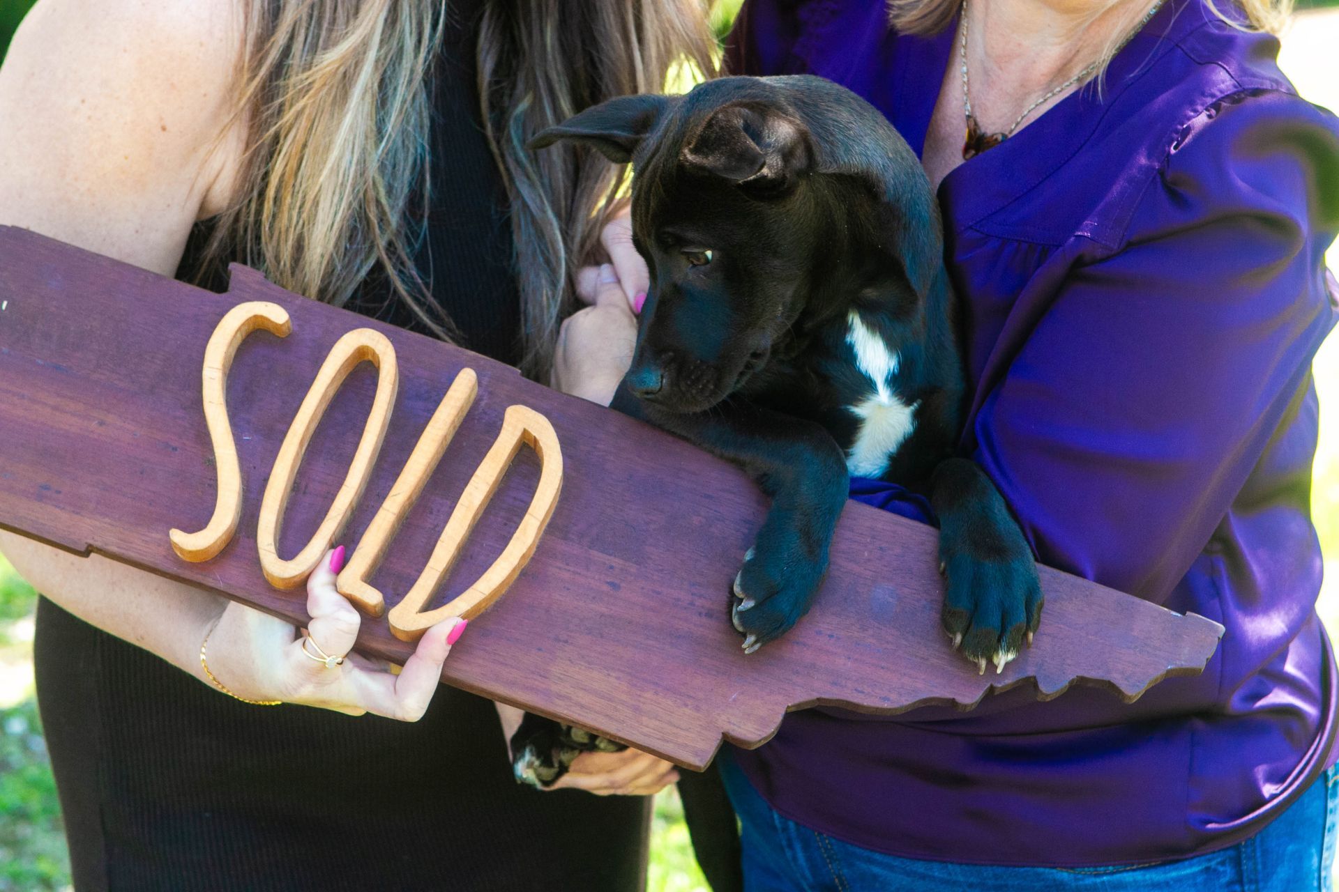 Muttz Realty team member holding sold sign with rescue dog at Nashville community event