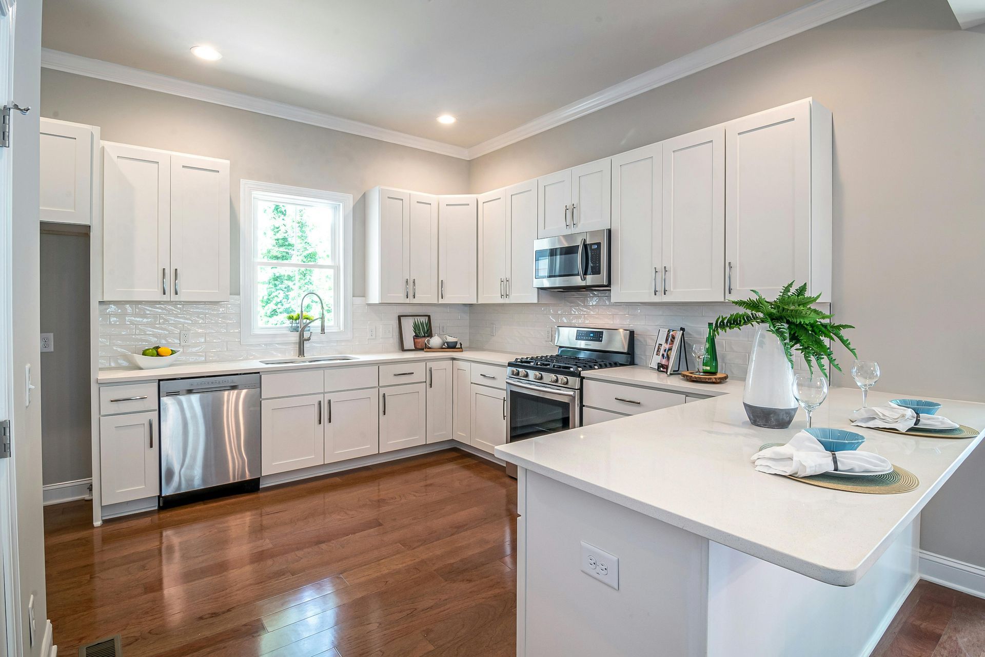 A kitchen with white cabinets , stainless steel appliances , and hardwood floors.