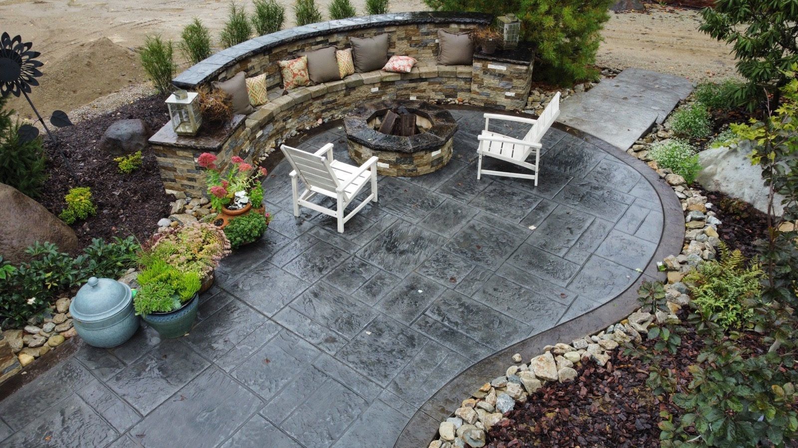 There is a fire pit in the middle of the patio with stamped concrete.