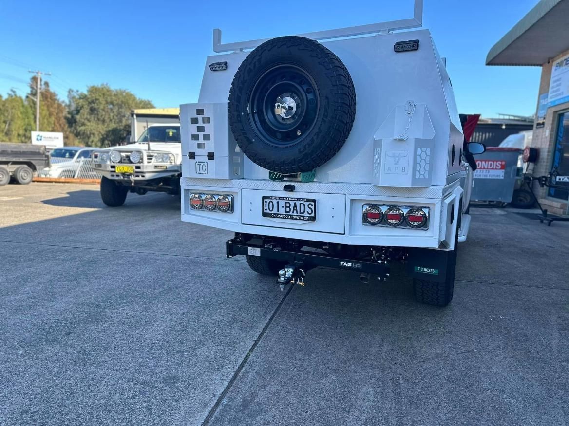 A white truck with a spare tire on the back is parked in a parking lot.