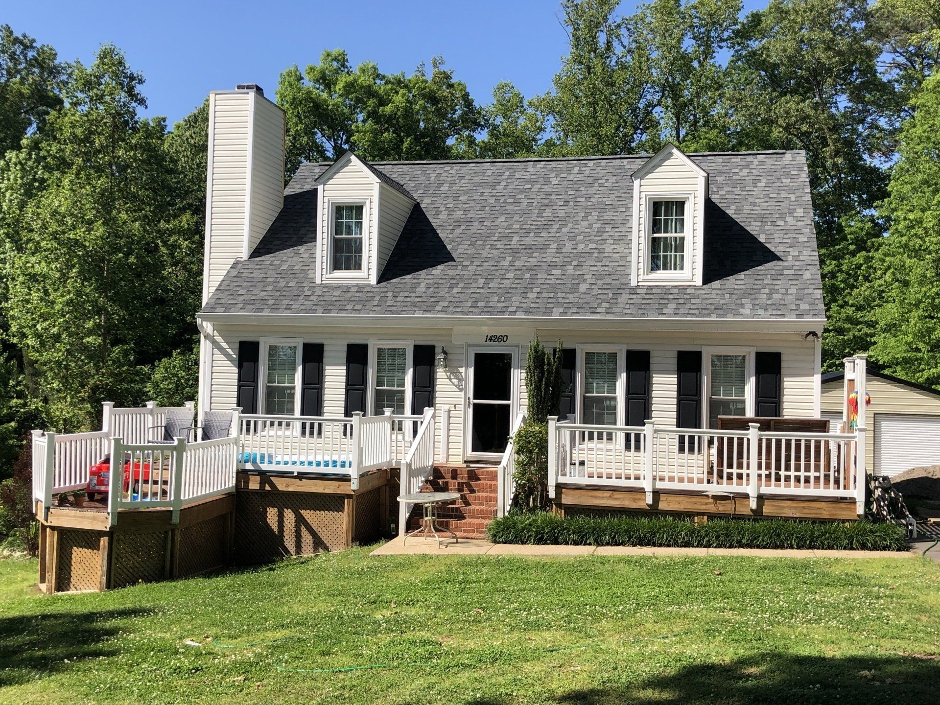 a white house with black shutters and a large deck .