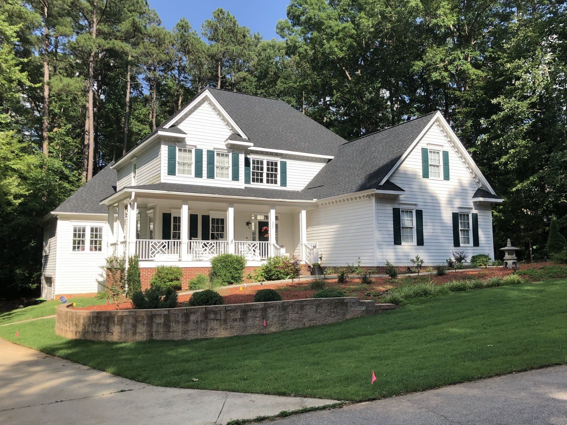 a large white house with a black roof and green shutters