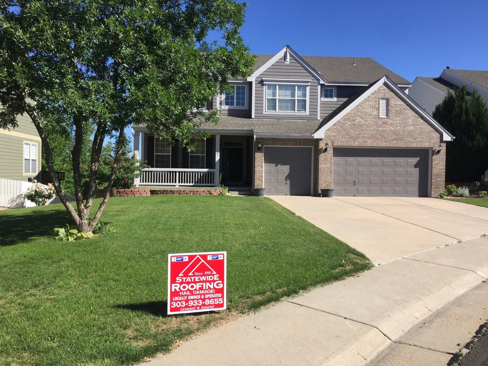 a house with a roofing sign in front of it .