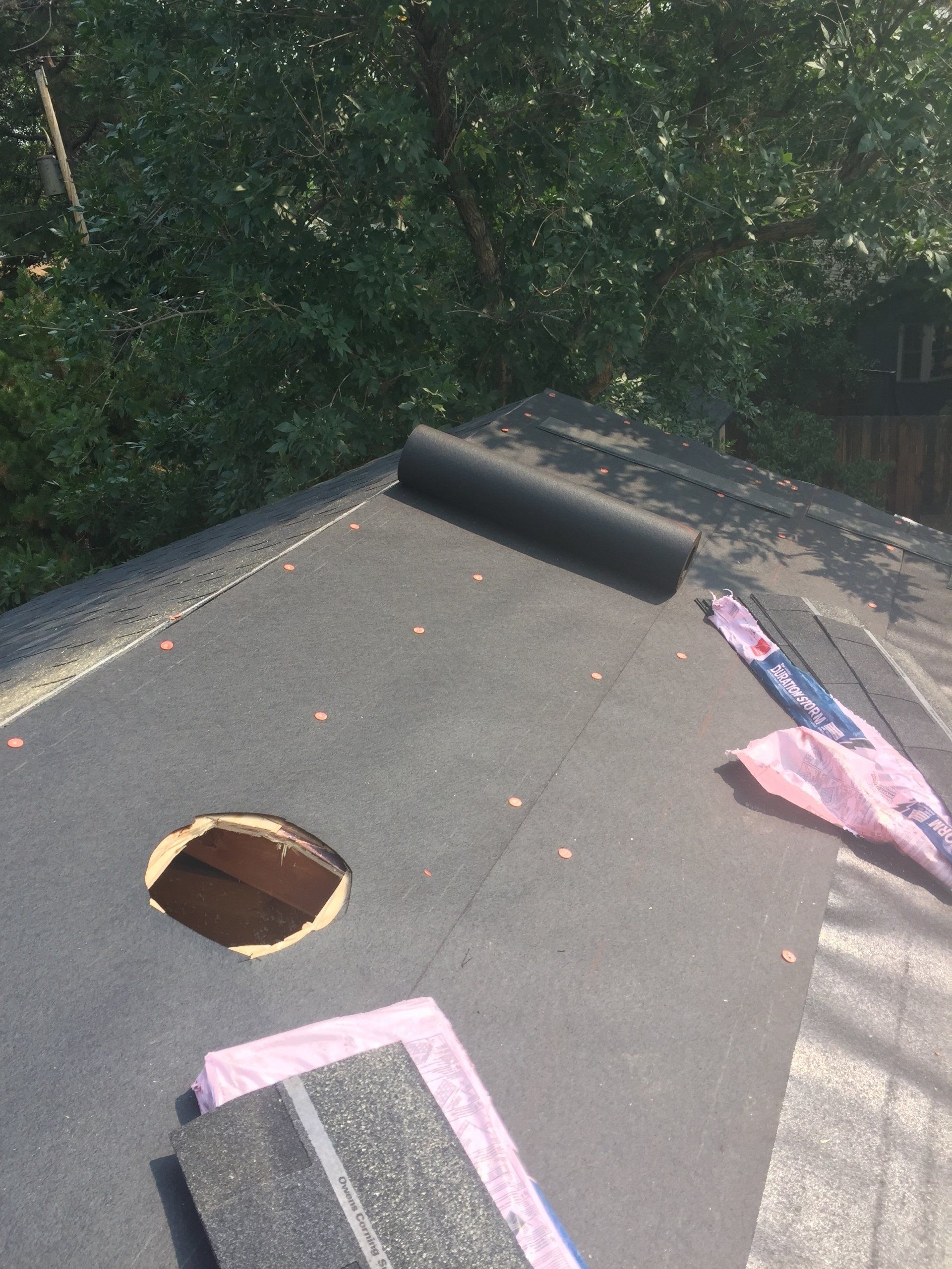 a roof with a hole in it and a roll of roofing material on it .