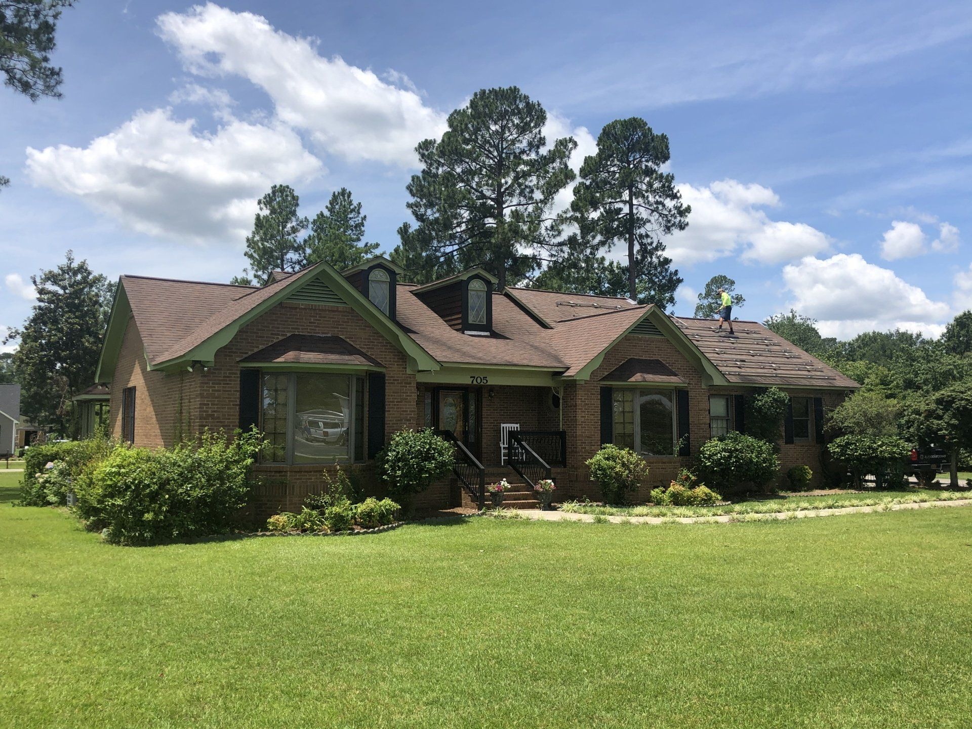 a large brick house with a brown roof is sitting on top of a lush green field .