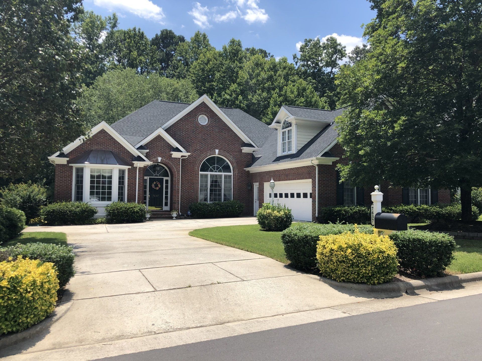 a large brick house with a black roof and a driveway