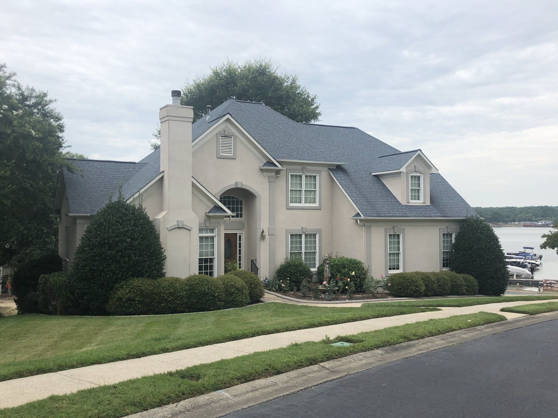 a large white house with a blue roof is next to a body of water .