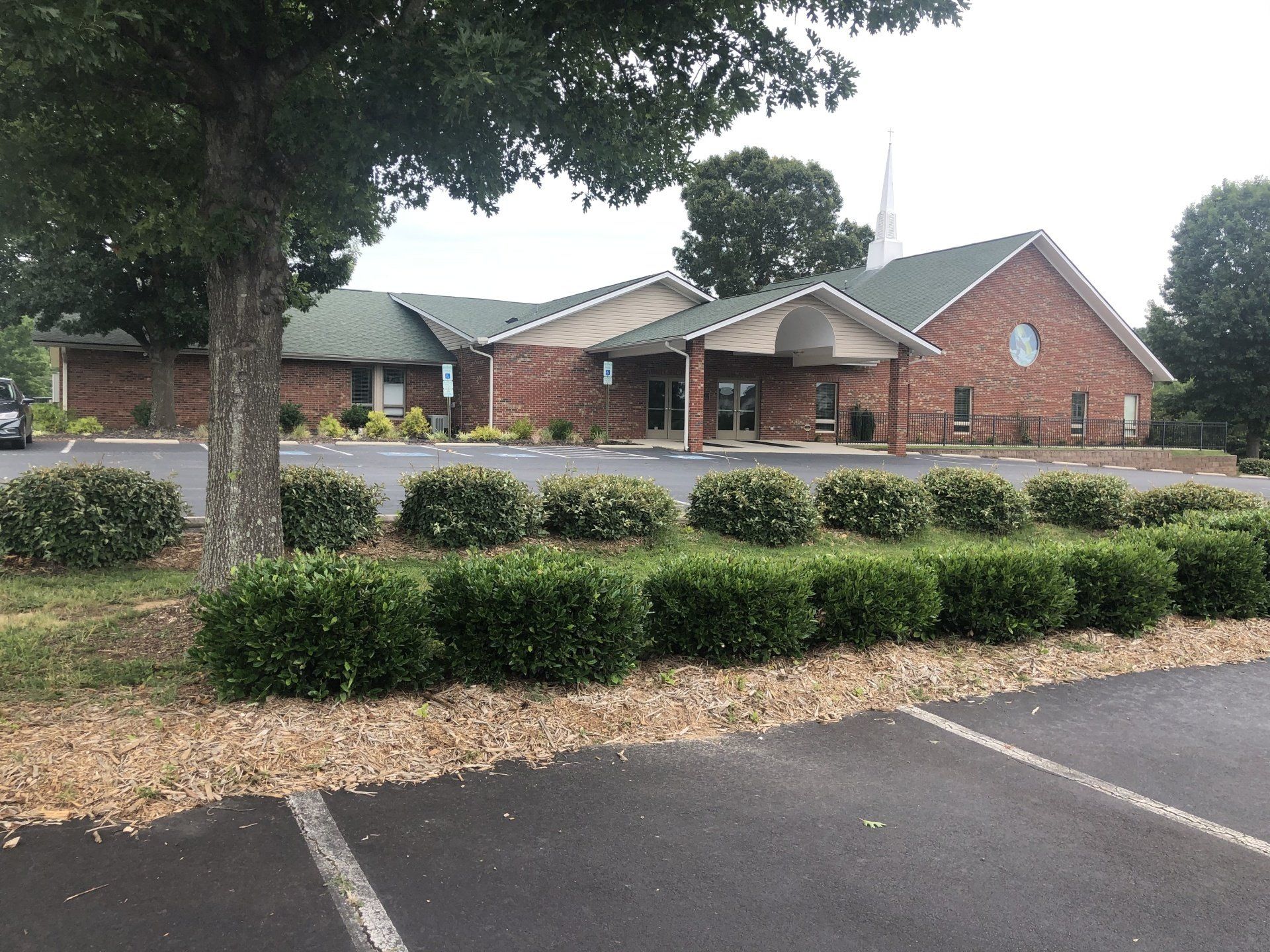 a brick building with a green roof and a parking lot in front of it
