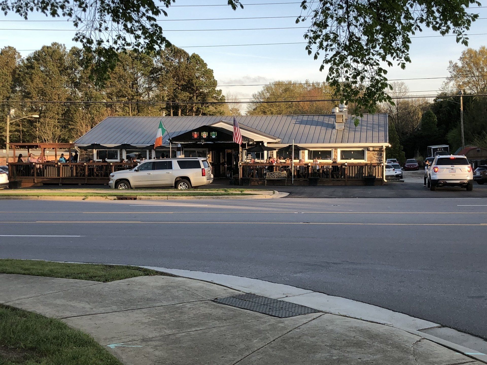 a white suv is parked on the side of the road in front of a restaurant .