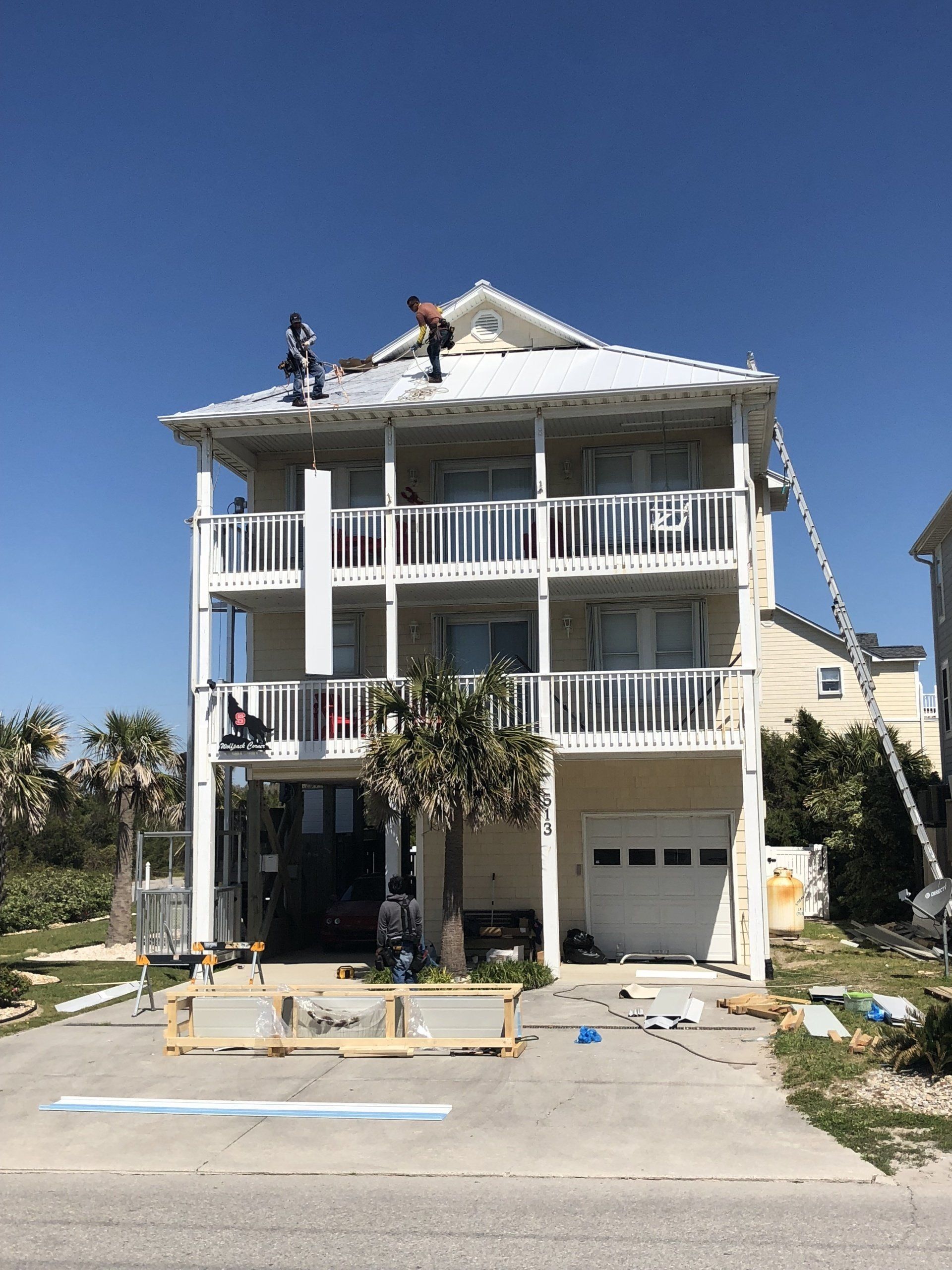 a large white house is being painted with a blue sky in the background .