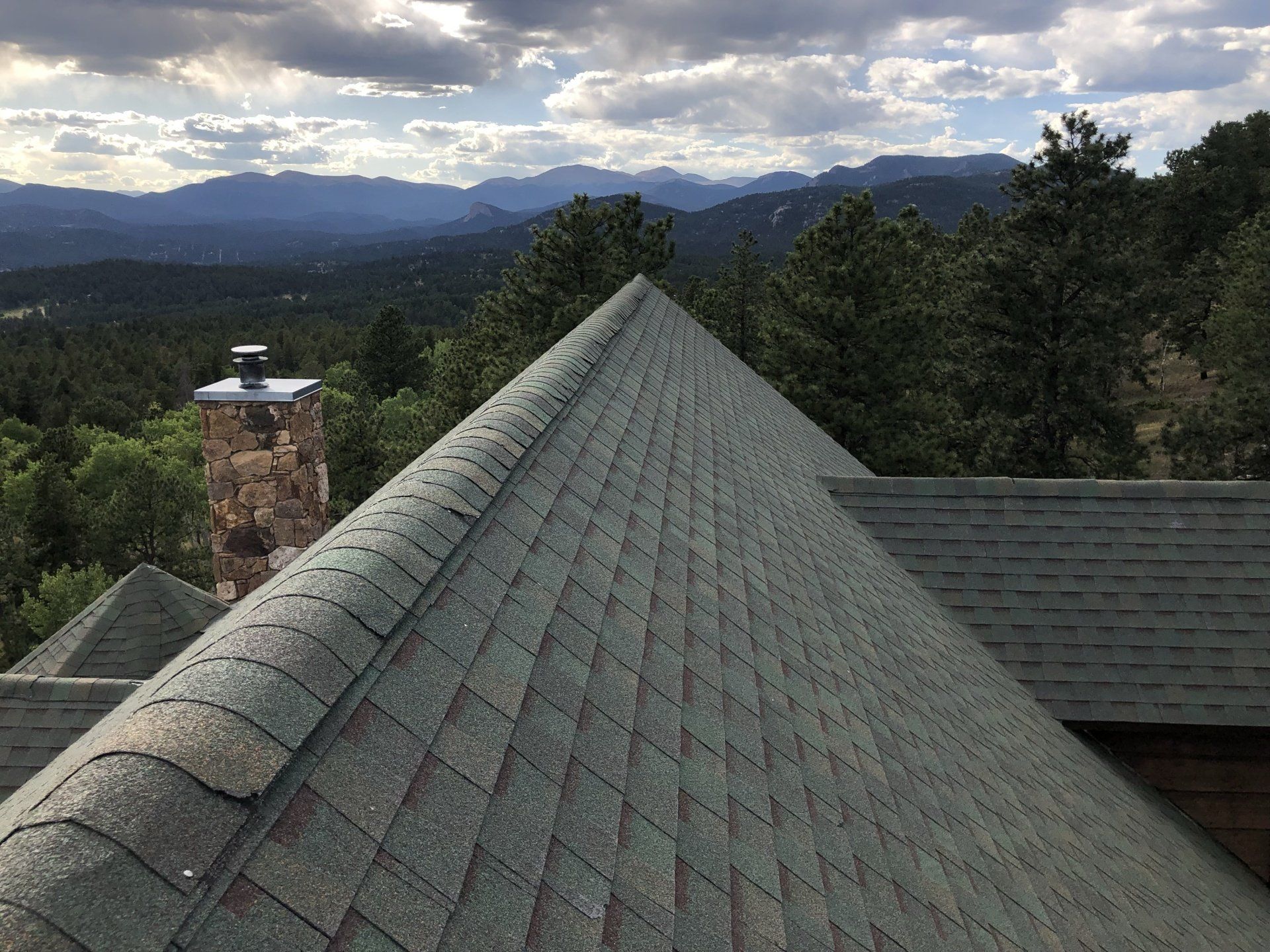 the roof of a house with a view of the mountains and trees .