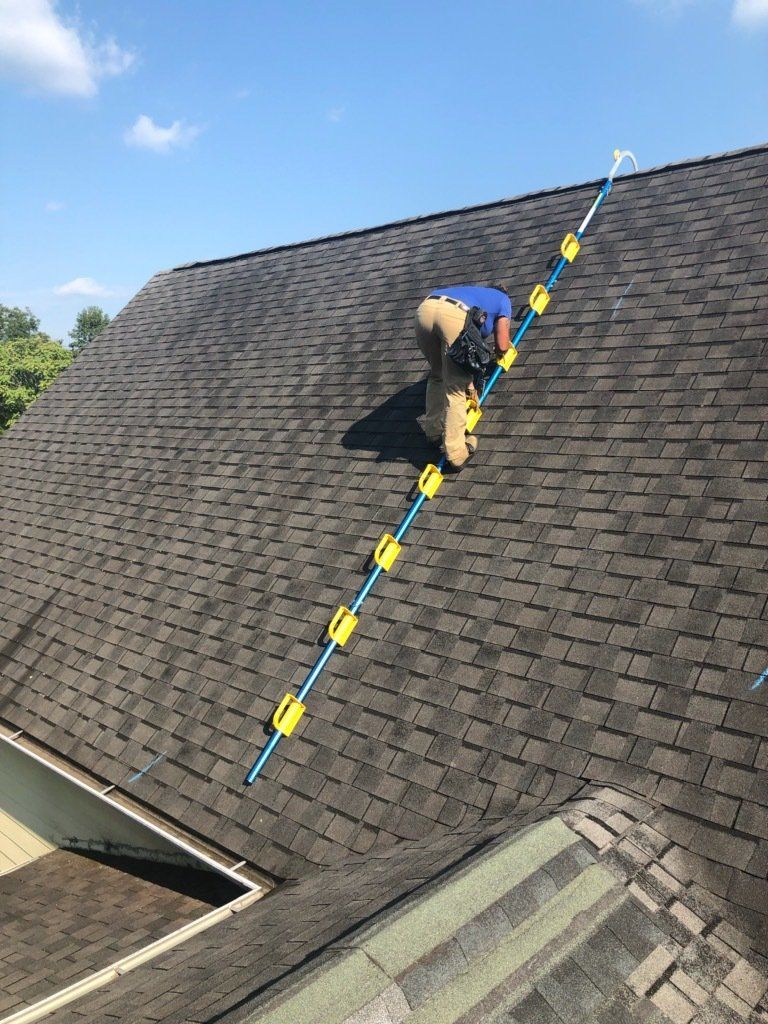 a man is standing on top of a roof with a ladder .