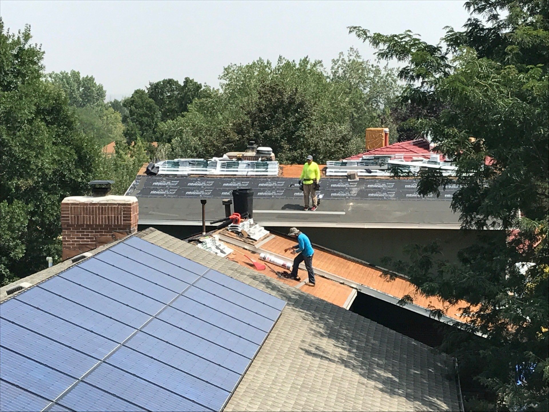 a man is working on the roof of a house with solar panels .