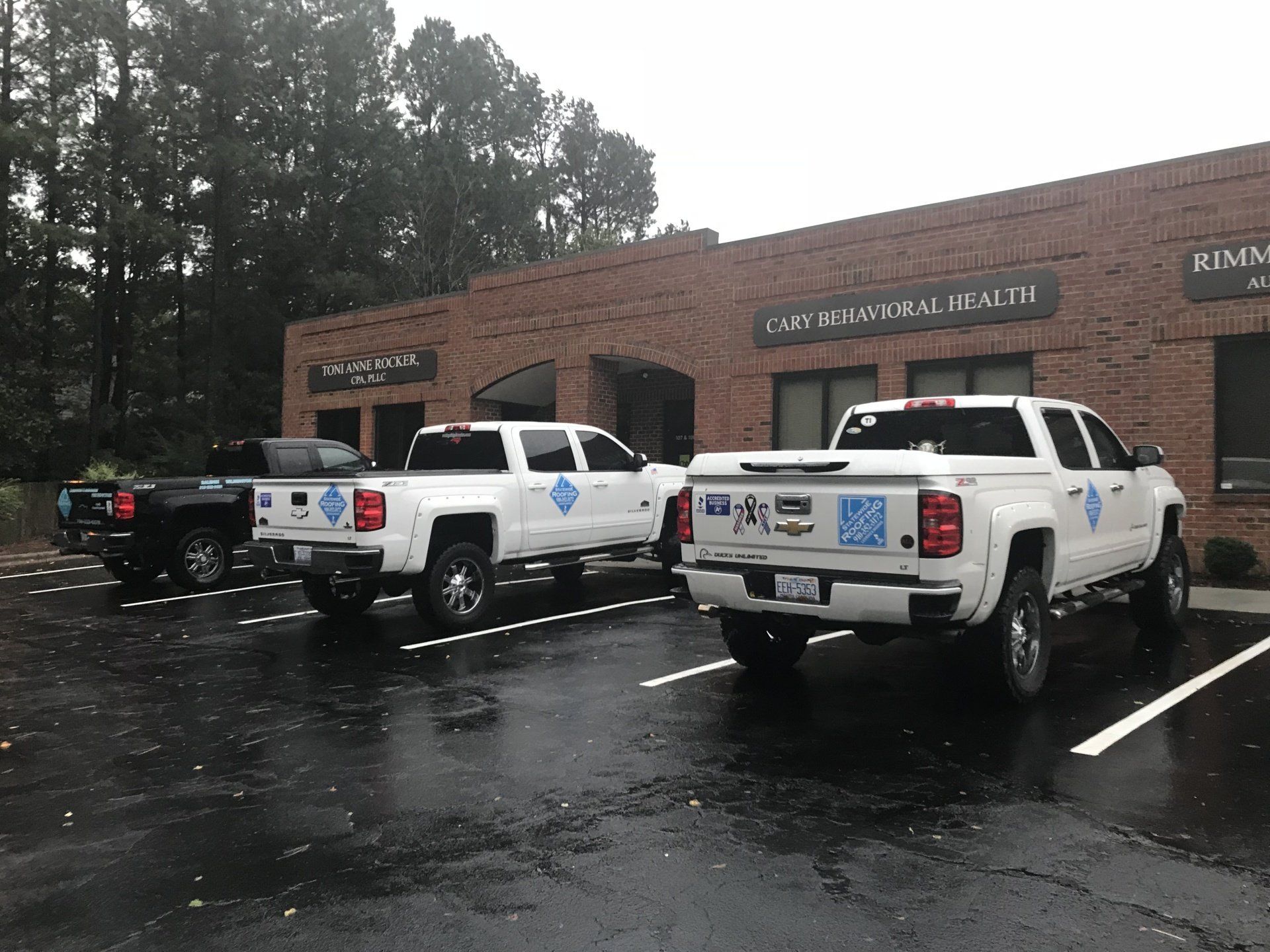 three white trucks parked in front of a brick building