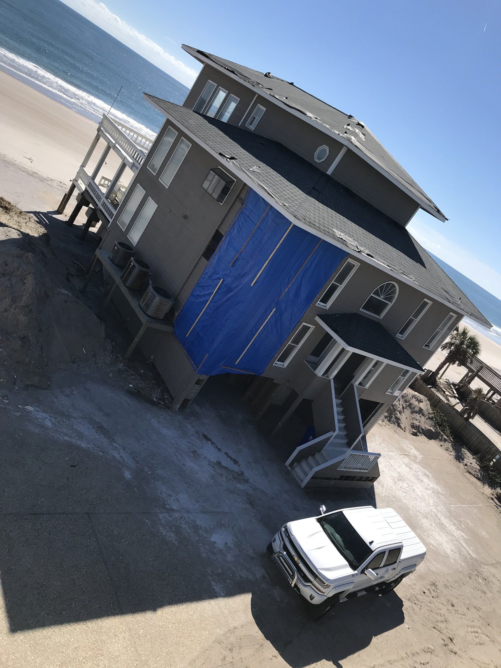 a white truck is parked in front of a house on the beach