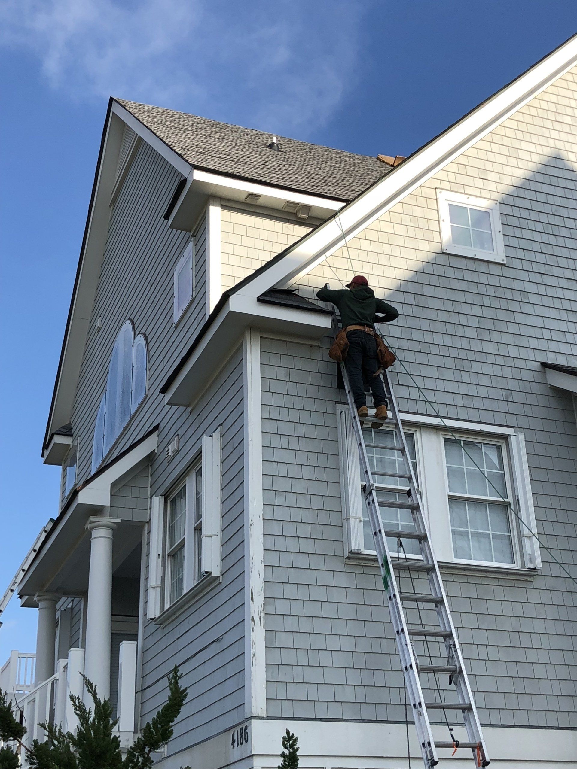 a man is standing on a ladder on the side of a house .