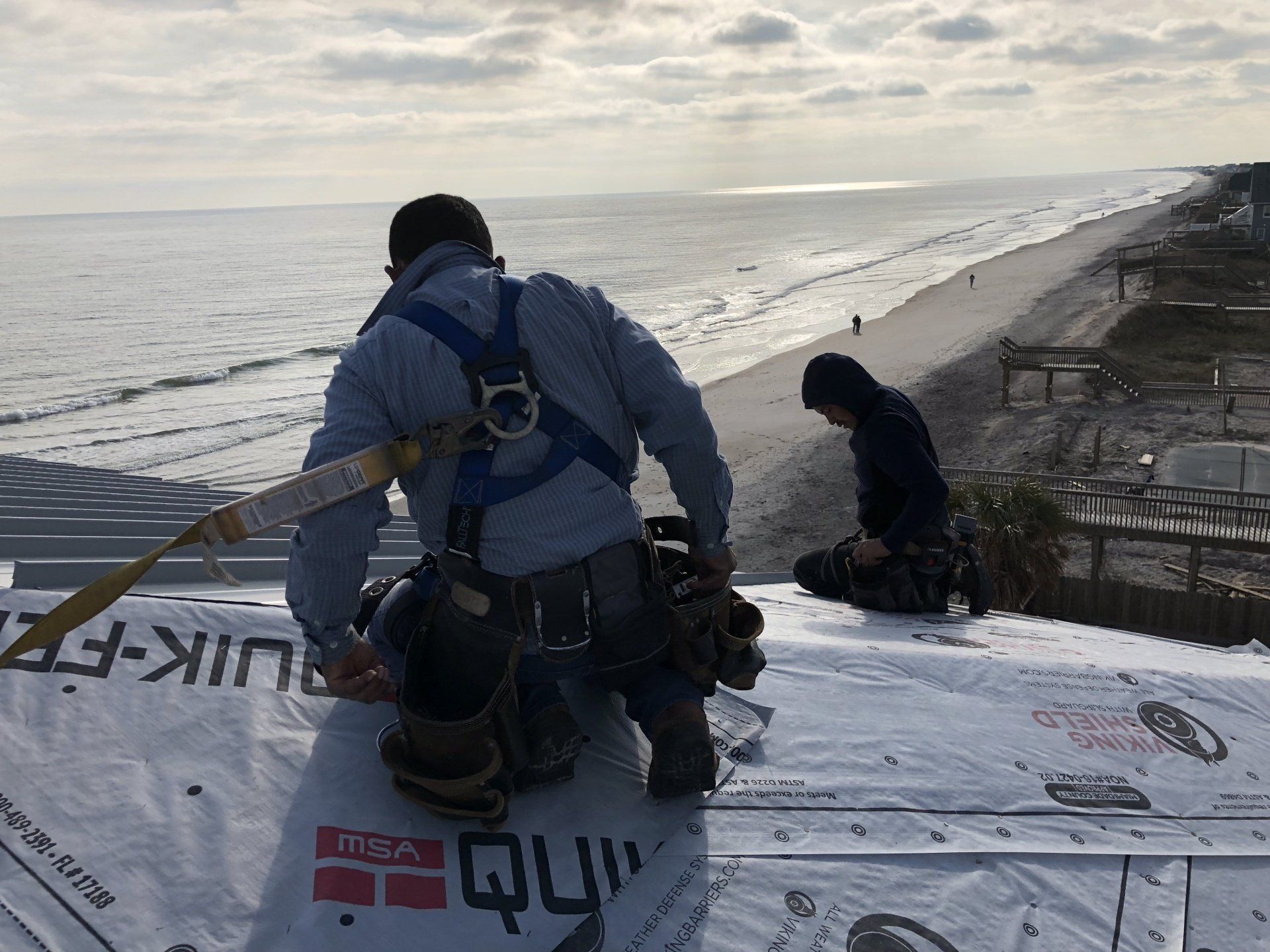 two men are working on a roof overlooking the ocean .