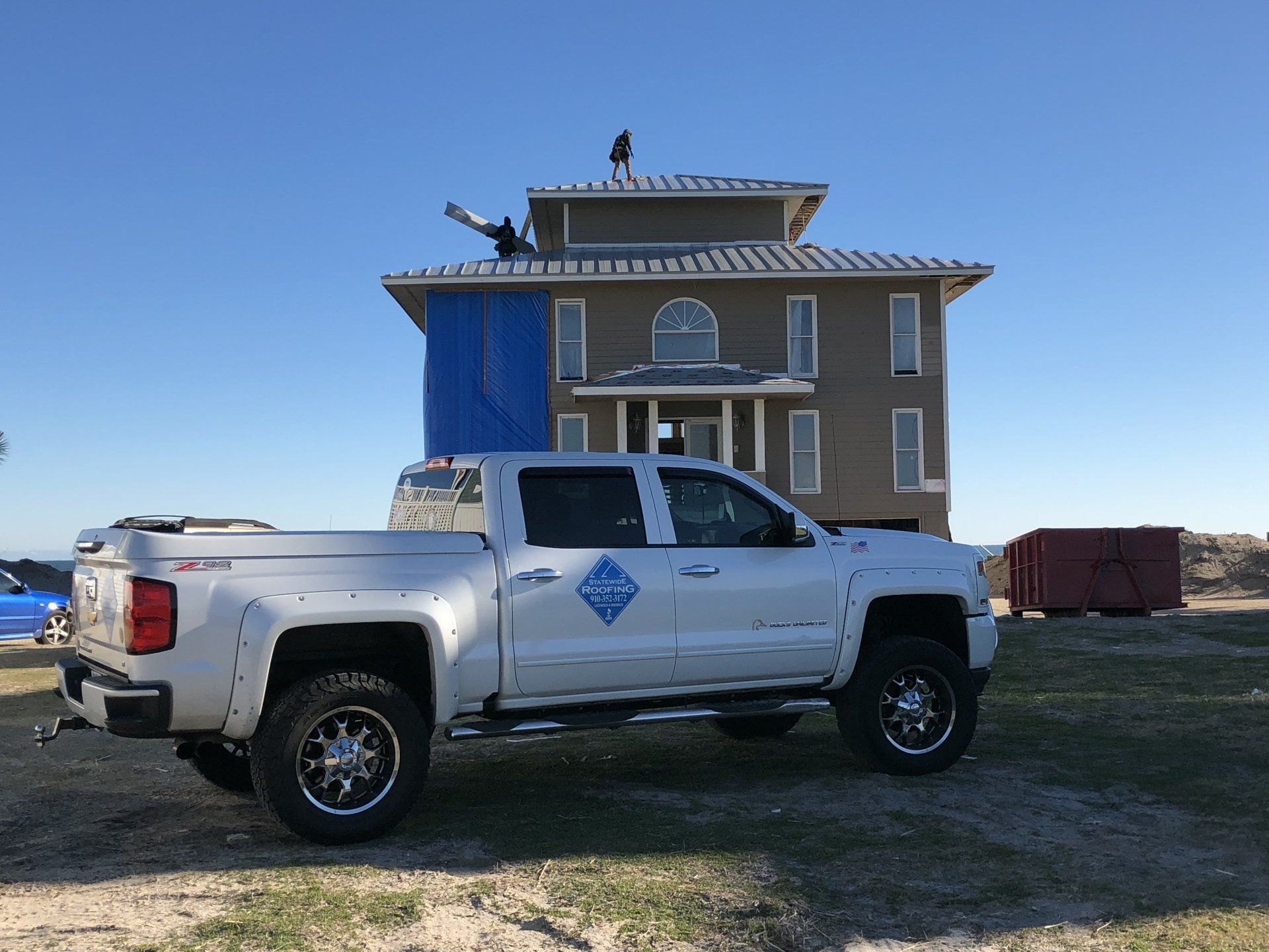 a white Statewide Roofing truck is parked in front of a house under construction