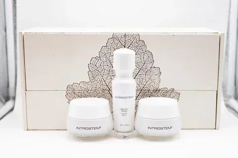 Skincare set with white jars and bottle in front of a box with a leaf design.