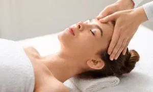 Woman receiving a head massage, eyes closed, in a spa setting.