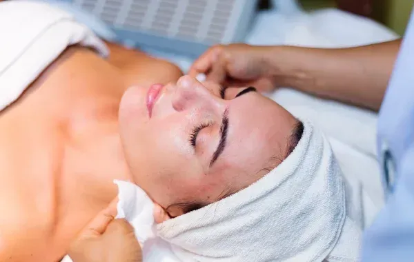 Woman receiving a facial, face covered with towel, lying on a spa bed.