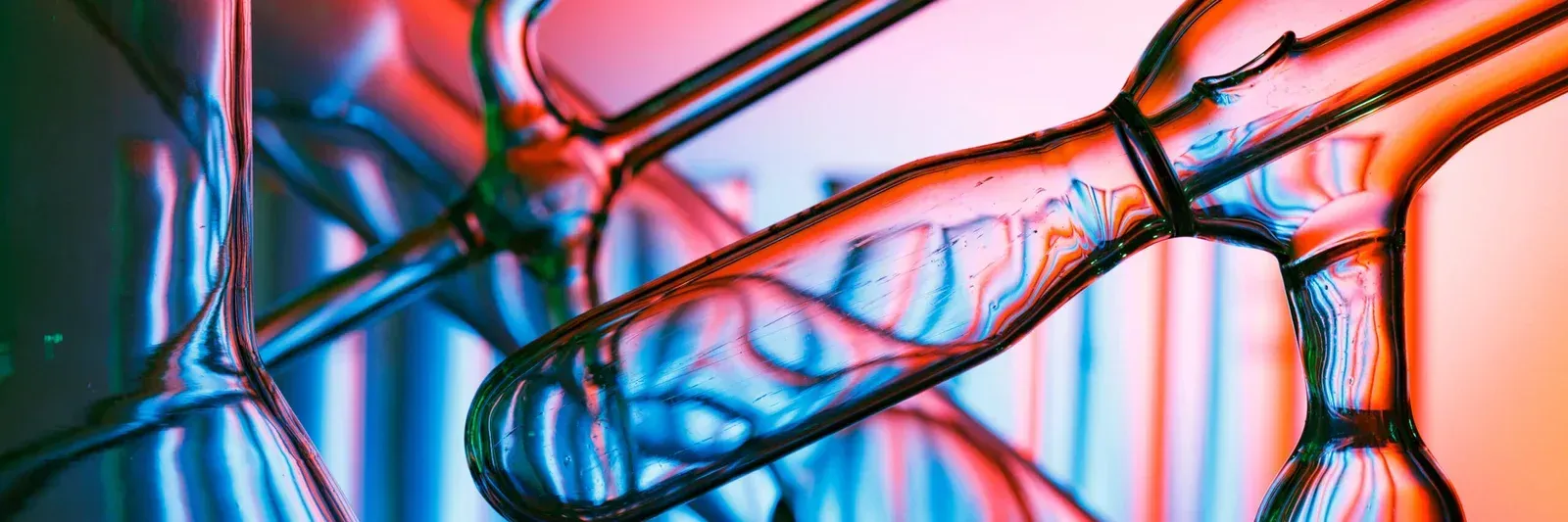 Close-up of glass lab equipment with red, orange, blue, and green lighting effects.