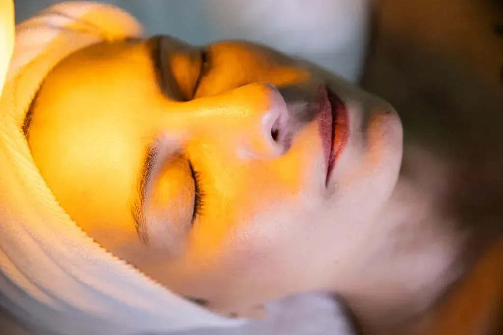 Woman with eyes closed, bathed in warm light, wrapped in a towel.