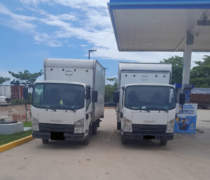 Camión Isuzu blanco con banderas canadienses y mexicanas frente a un edificio en un día soleado.