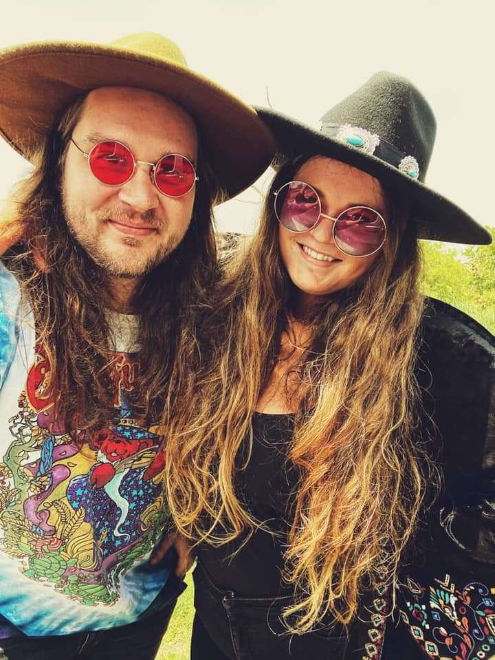 A man and a woman wearing hats and sunglasses are posing for a picture.