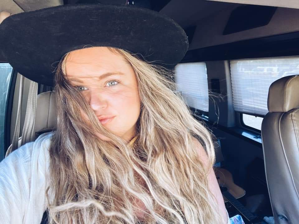 A woman wearing a black hat is sitting in a car