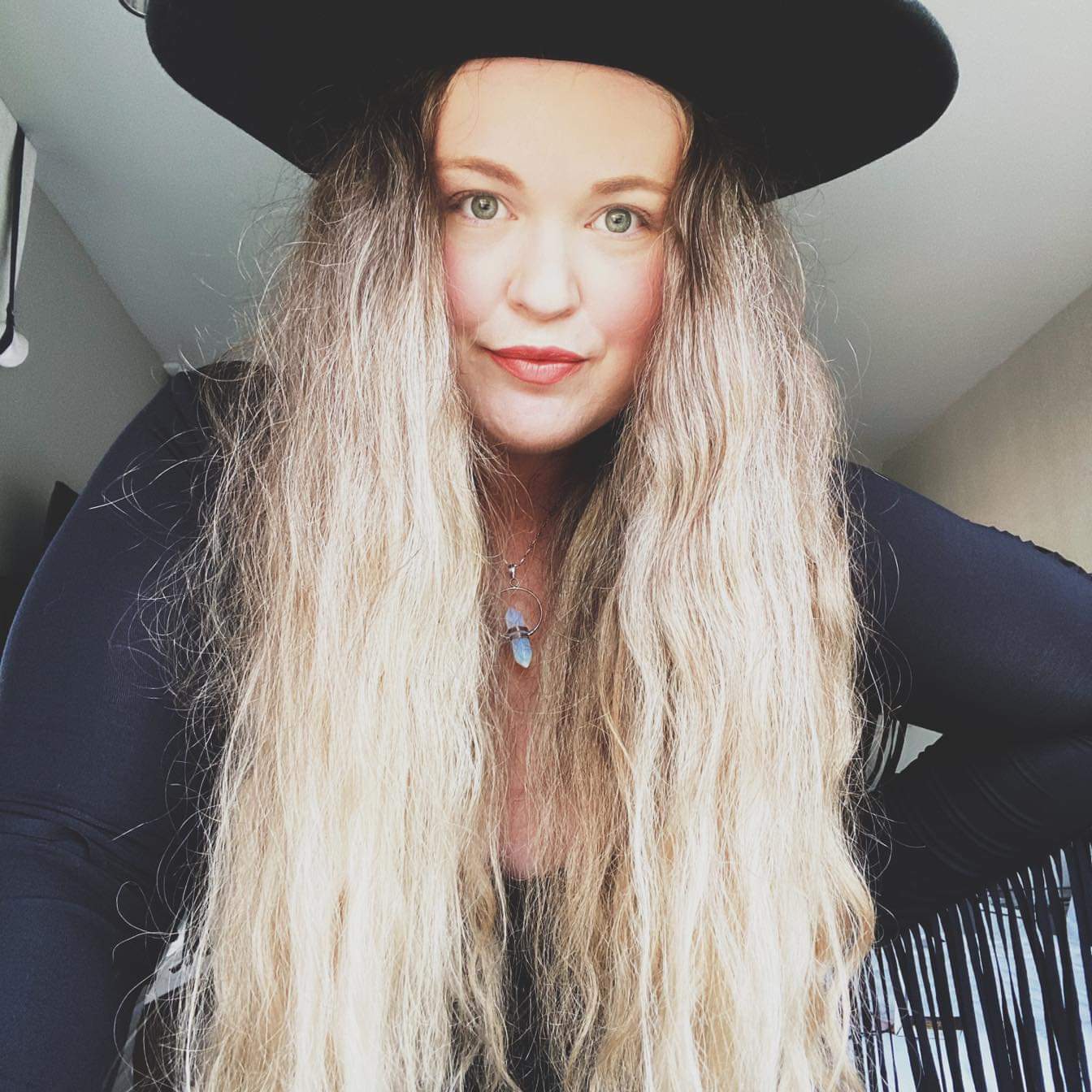 A woman with long blonde hair wearing a black hat