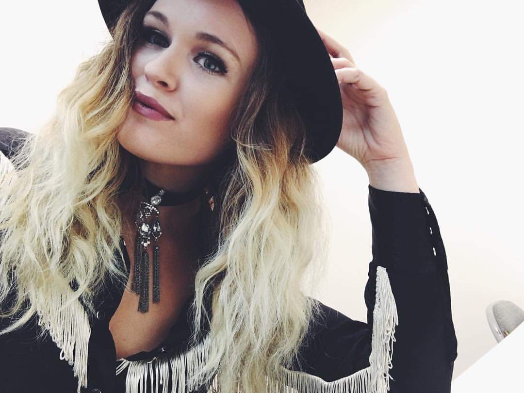 A woman wearing a black hat and fringed jacket