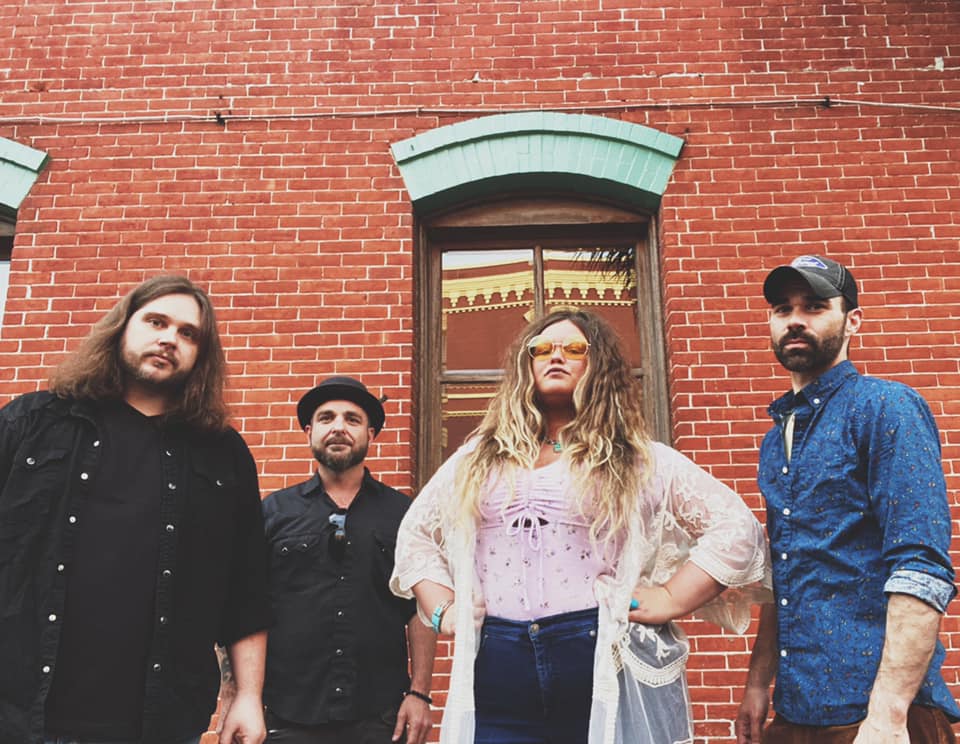A group of people are standing in front of a brick building.