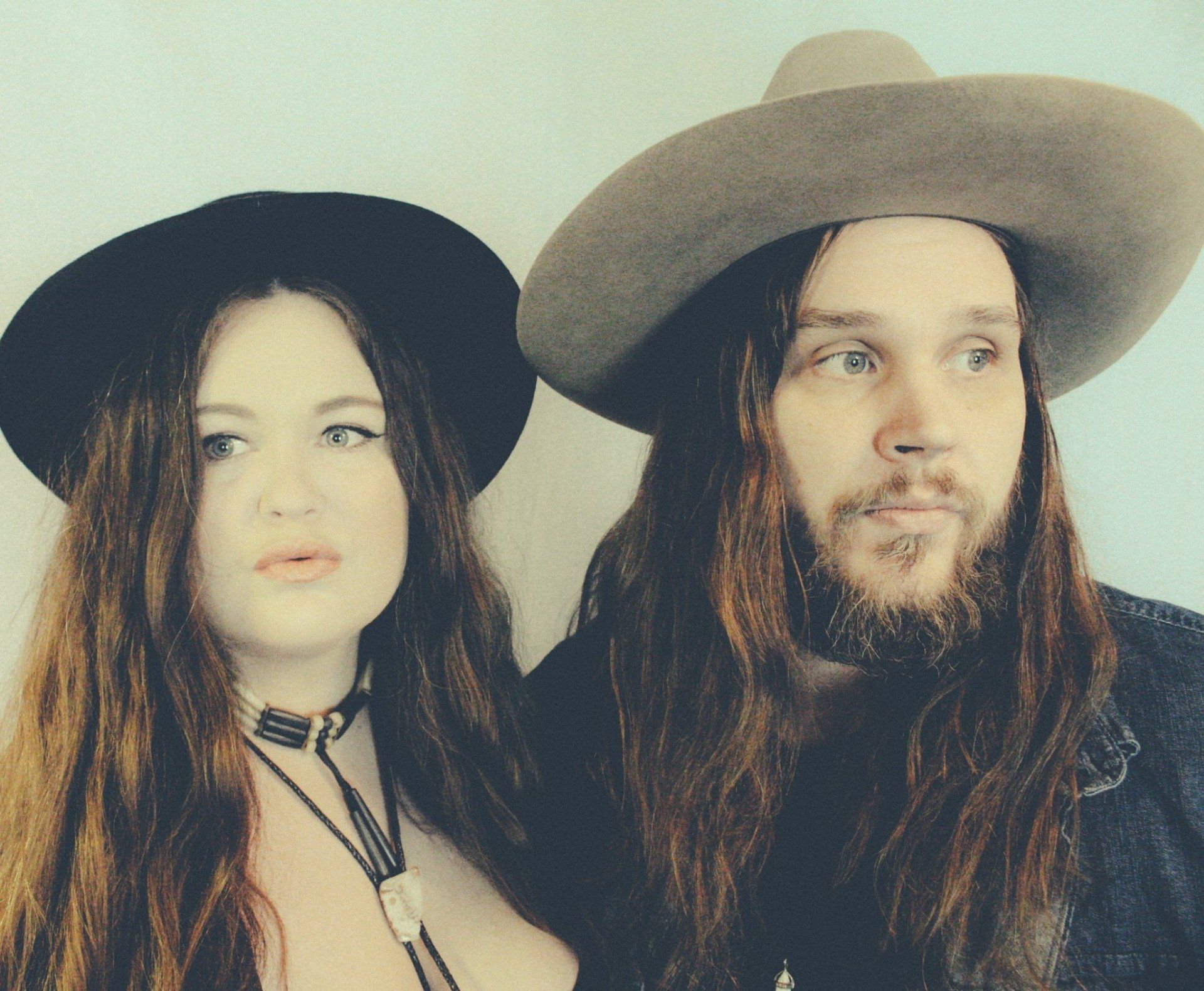 A man and a woman with long hair wearing hats