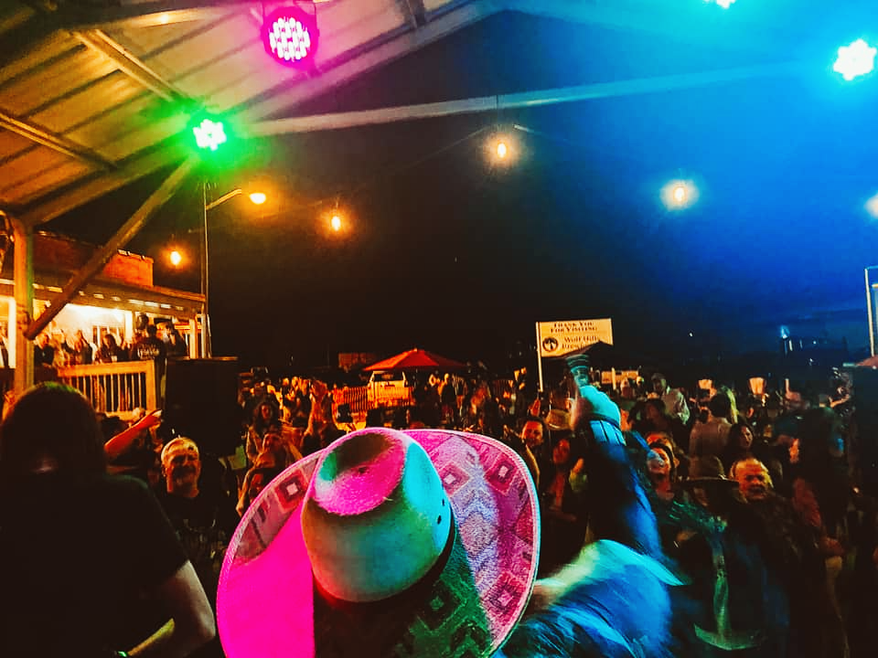 A person wearing a pink cowboy hat stands in front of a crowd