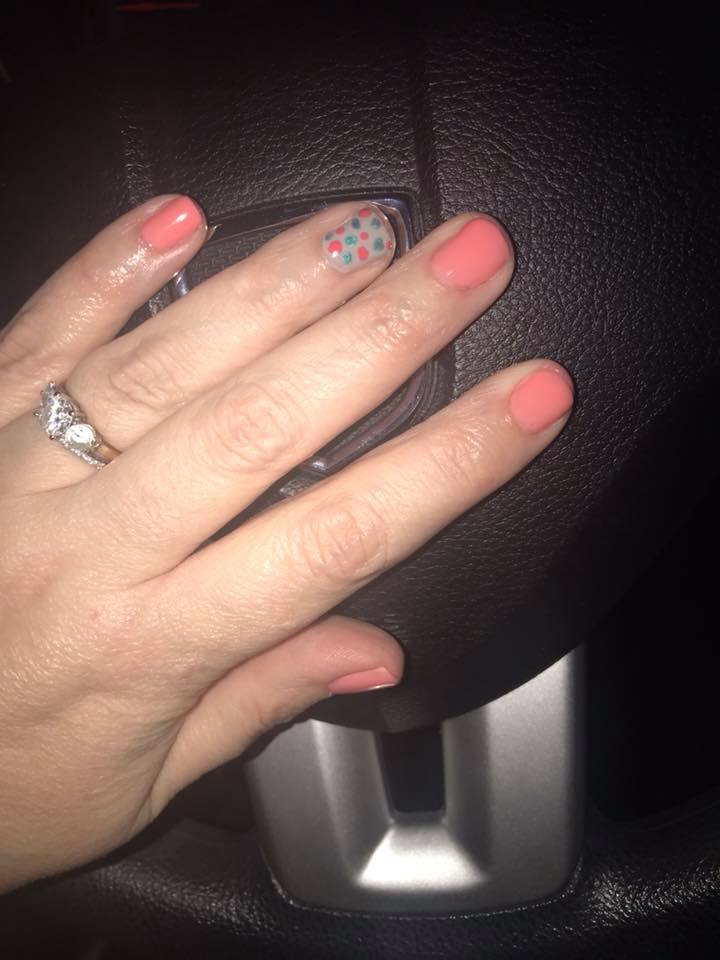 salmon pink manicure with blue and pink polka dot accent nail