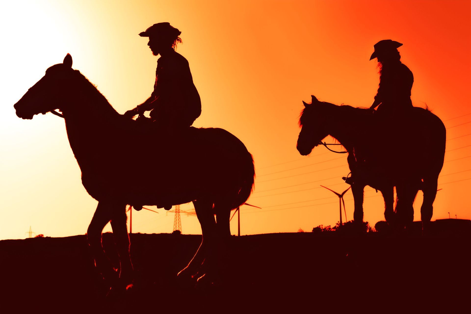 Two People Are Riding Horses In A Field At Sunset — Shellie's Country Wear In Forster, NSW