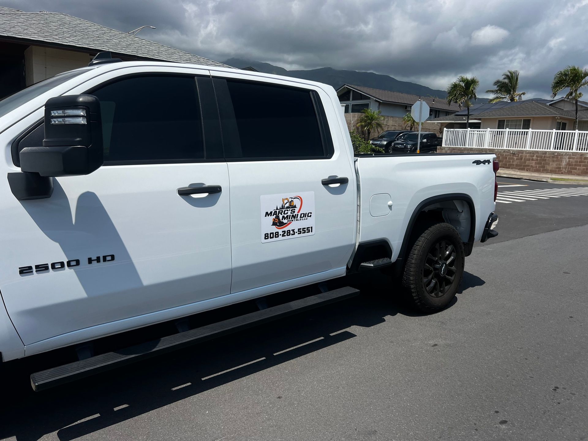 White Chevrolet 2500 HD pickup truck parked on a street with a business logo on the door.