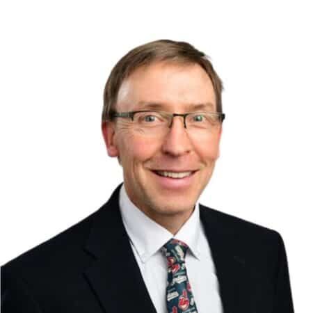 A smiling doctor in a lab coat with a stethoscope around his neck.