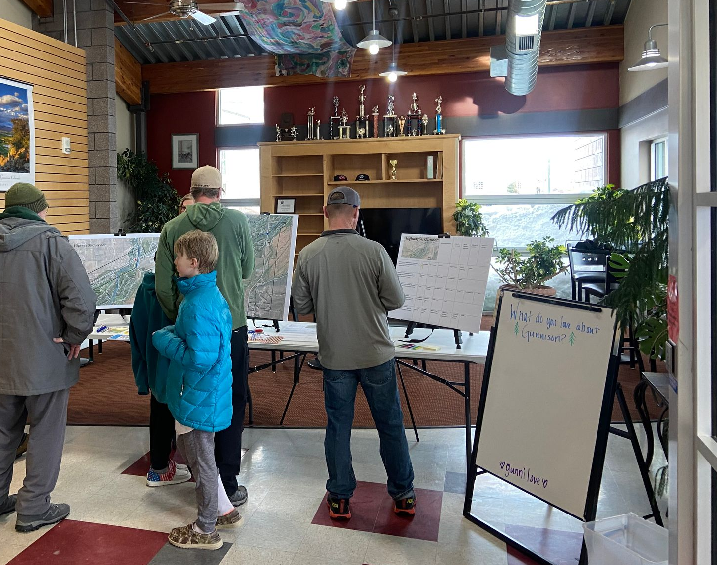people standing around white boards in a room with writing on the boards