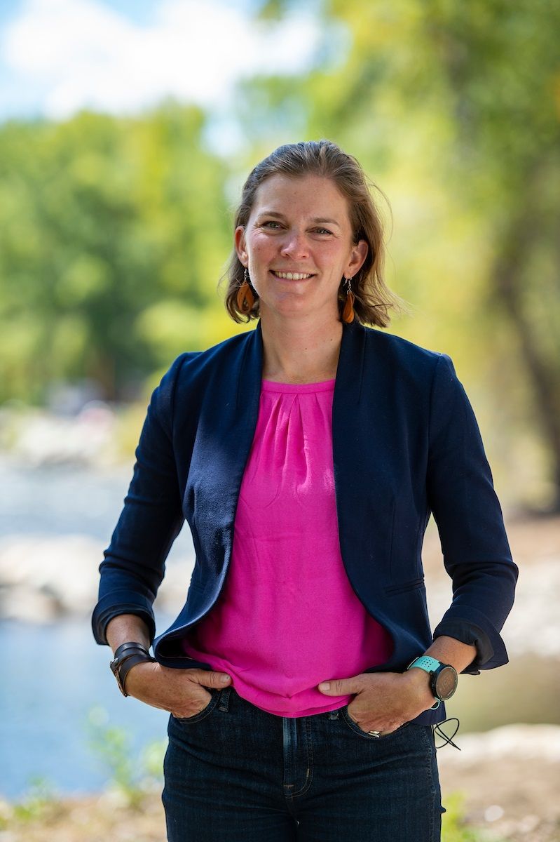headshot of woman standing in front of green aspen trees