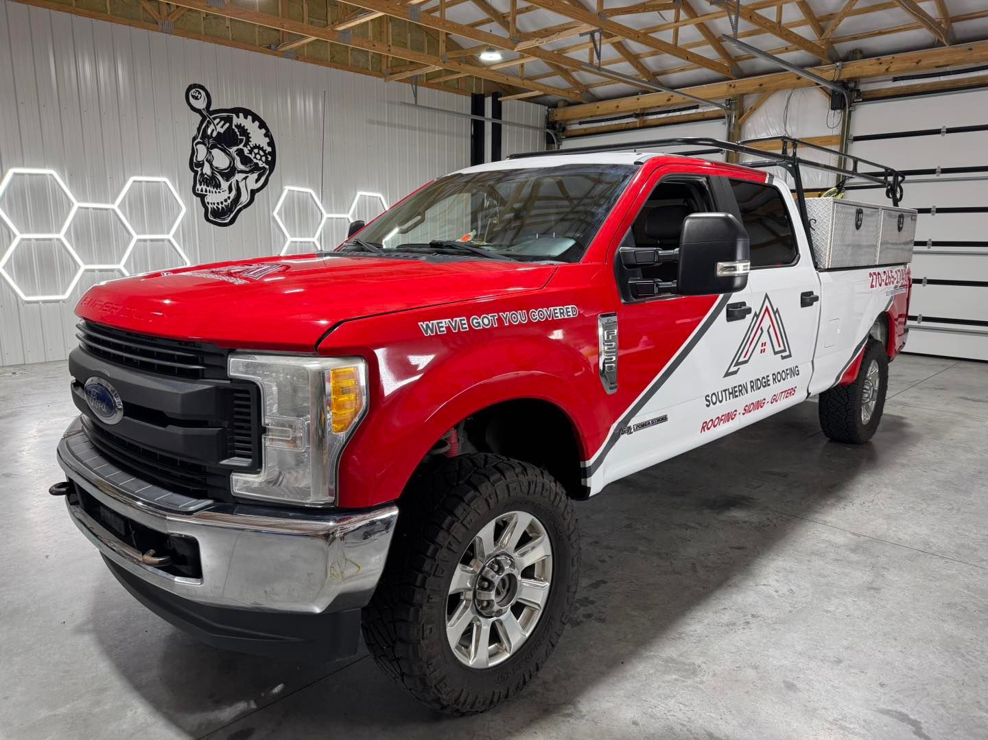 Red and white Ford pickup truck with company logo parked inside a building.